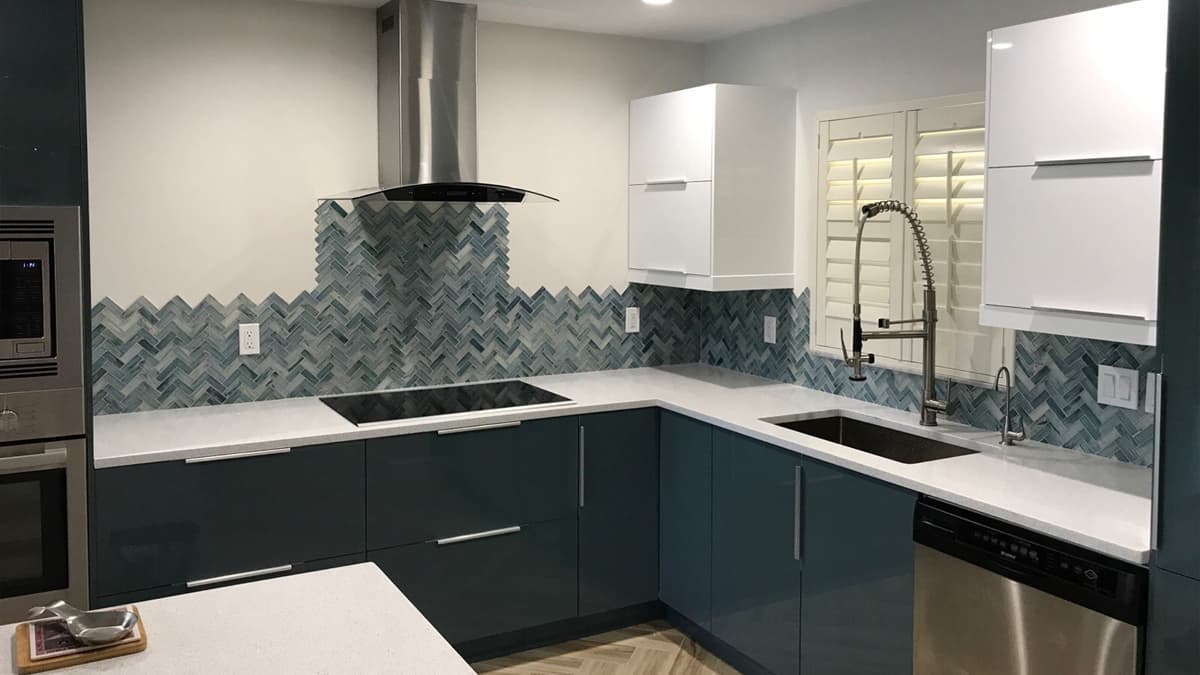 Kitchen remodel by Villa d'Este with gloss cabinetry and a herringbone glass-tile backsplash